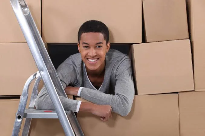 Student surrounded by packed boxes ready for storage