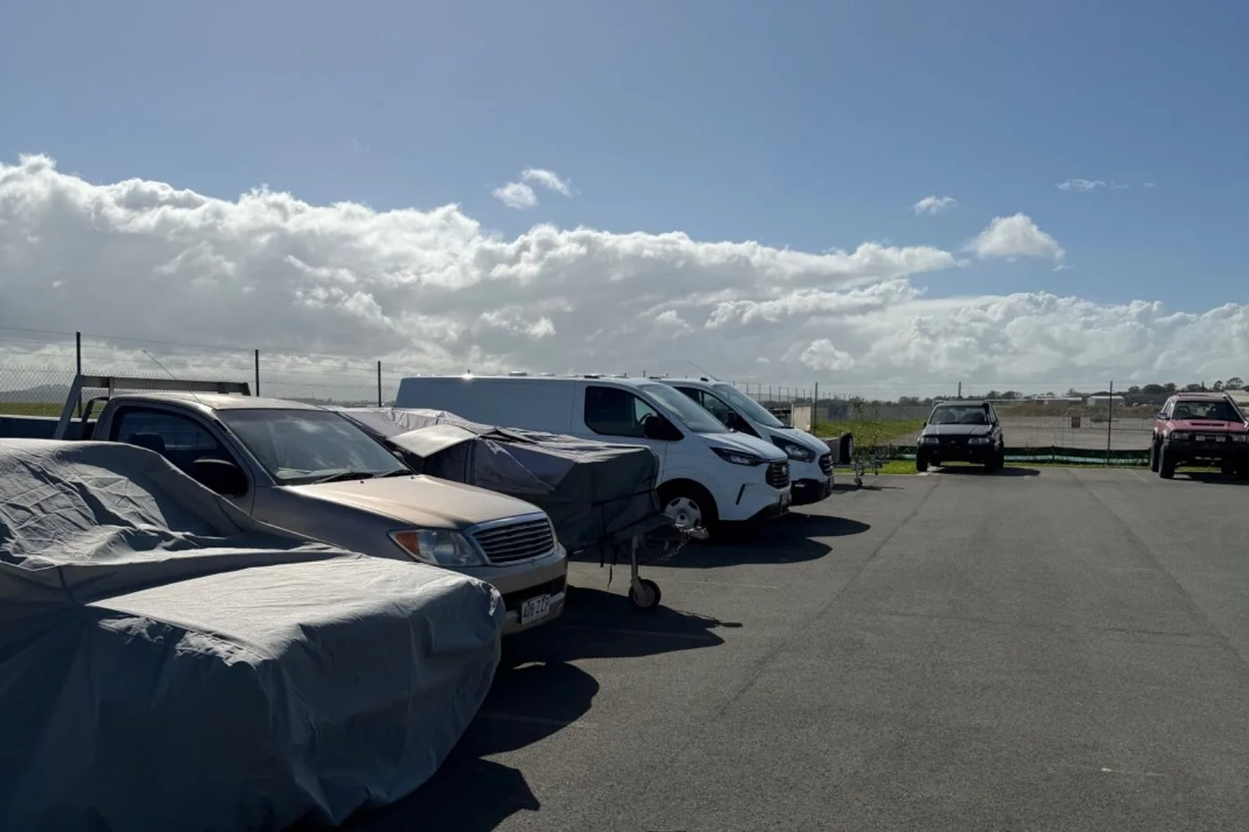 Covered cars and vans parked in open-air vehicle storage bays at Storage Land, Archerfield Brisbane